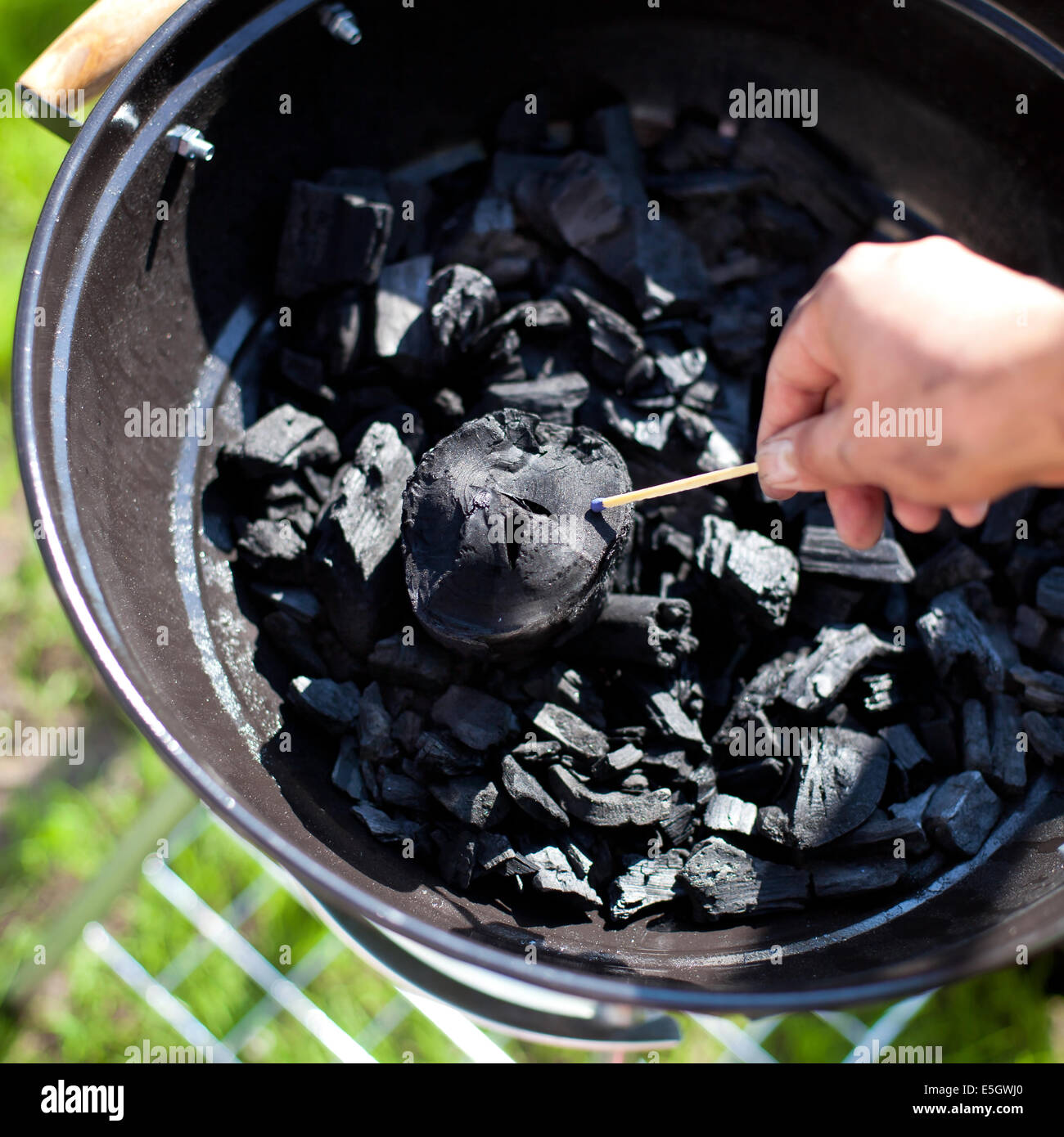 Striking a matchstick, burn up a charcoal in barbecue grill, prepare