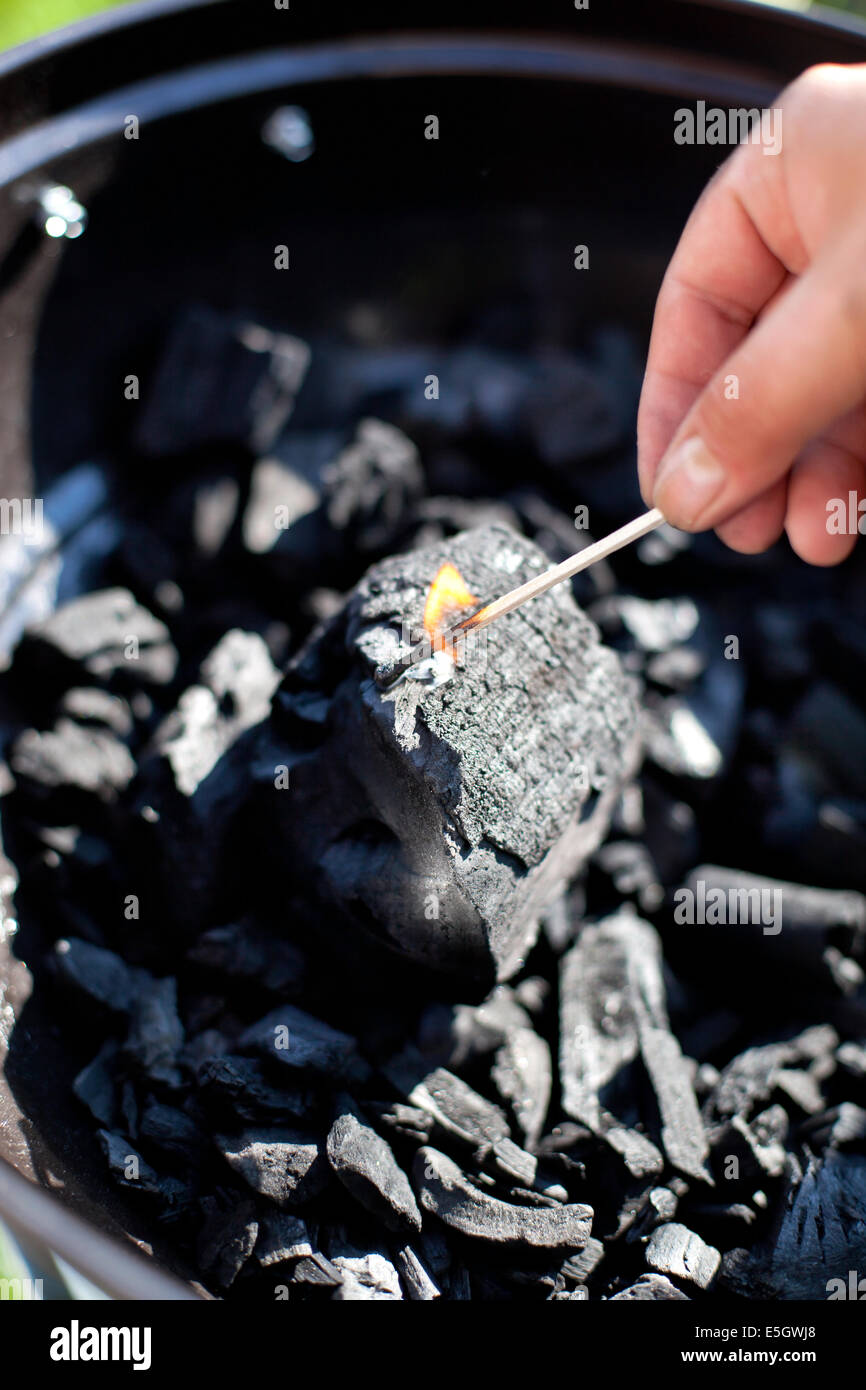 Striking a matchstick, burn up a charcoal in barbecue grill, prepare