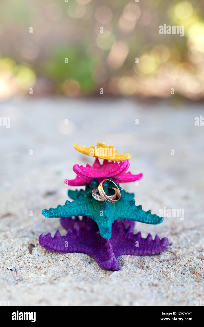 Gold wedding rings on color starfishes on white beach. Wedding Vacation concept Stock Photo