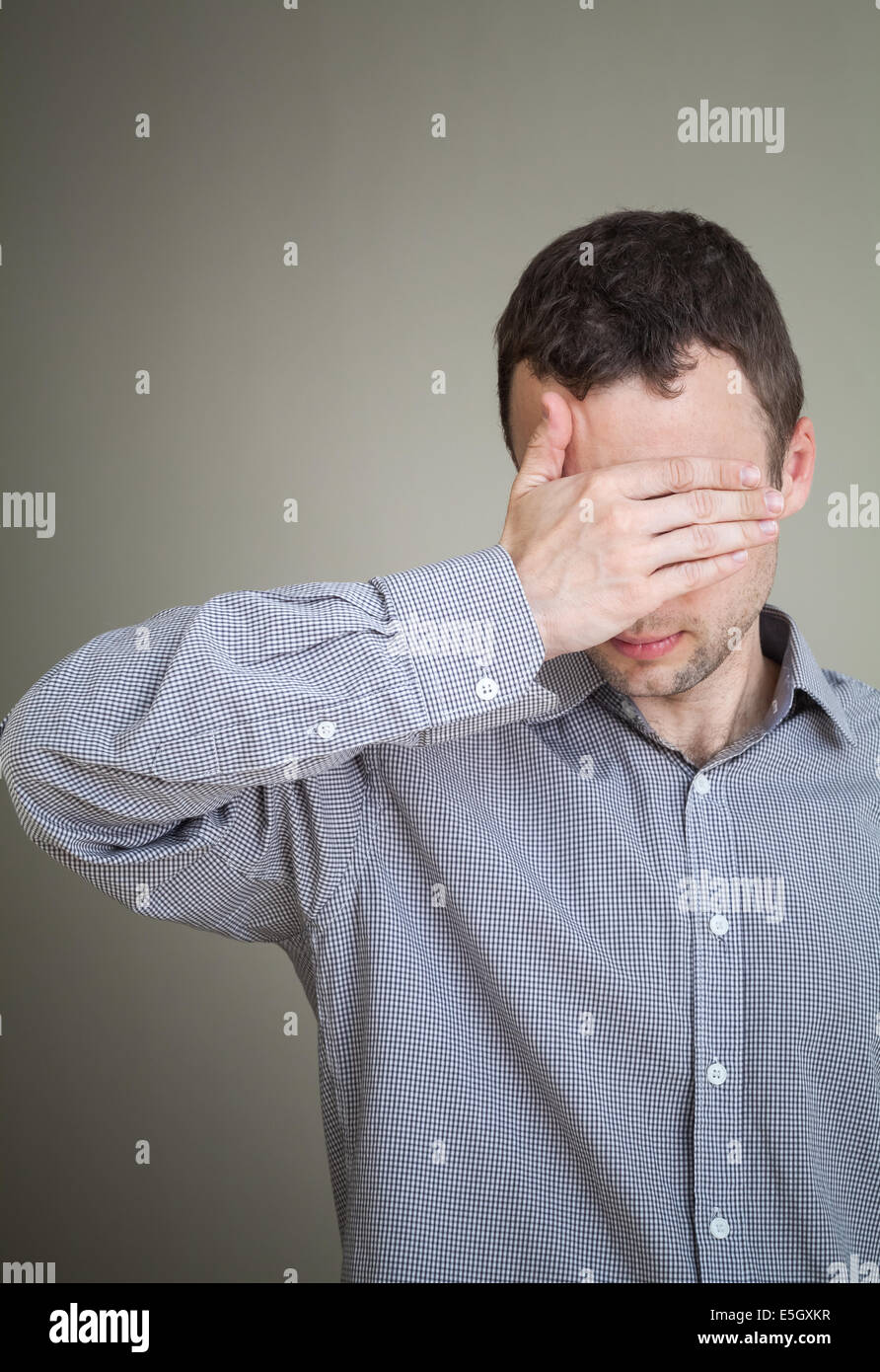 Young sad Caucasian man hiding his face with hand Stock Photo