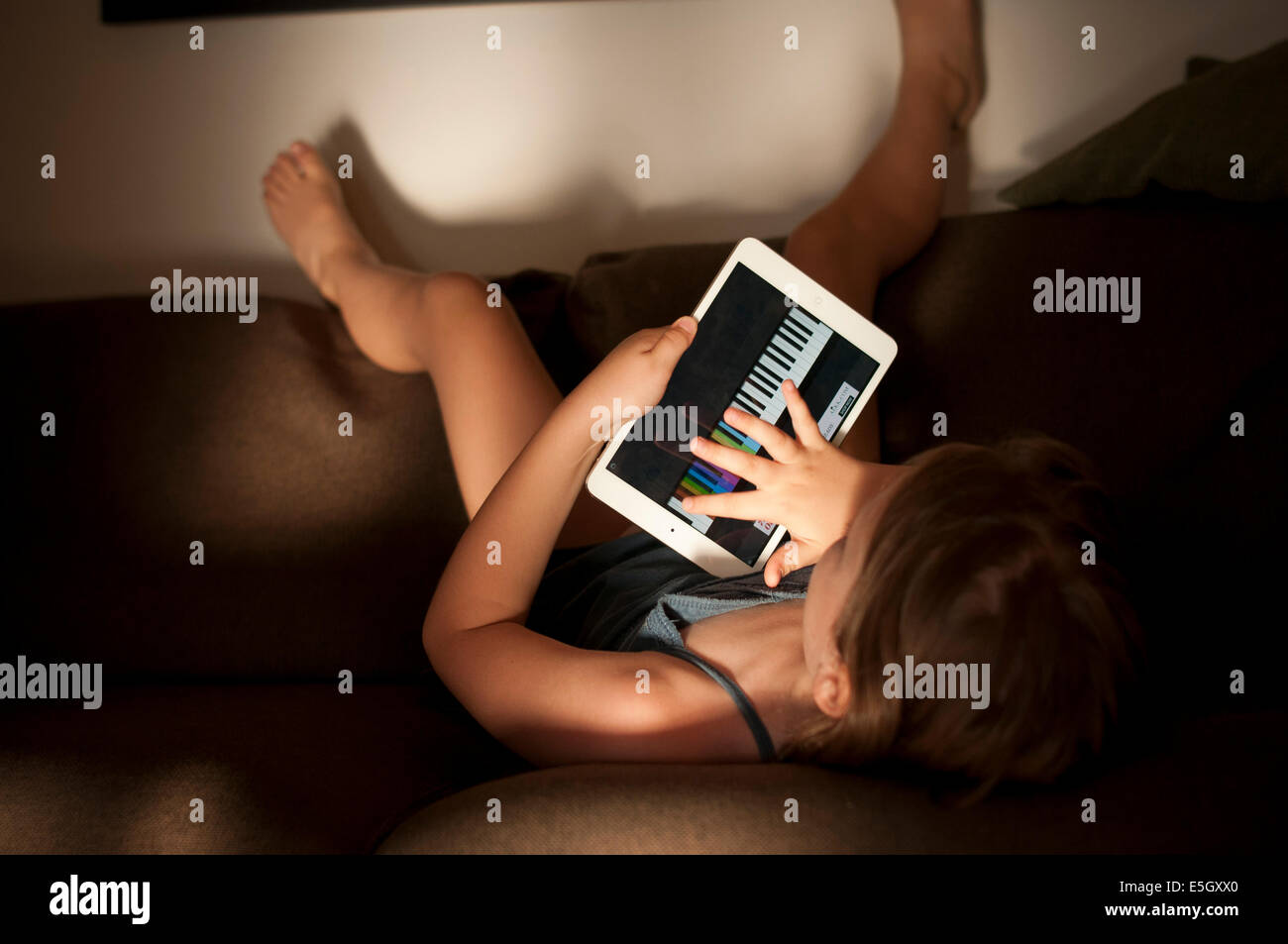 Six year old girl using an ipad mini tablet computer at home. Stock Photo