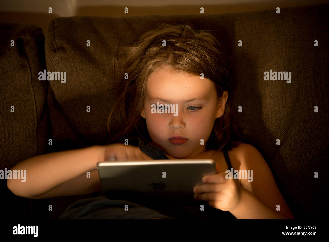 Six year old girl using an ipad mini tablet computer at home. Stock Photo