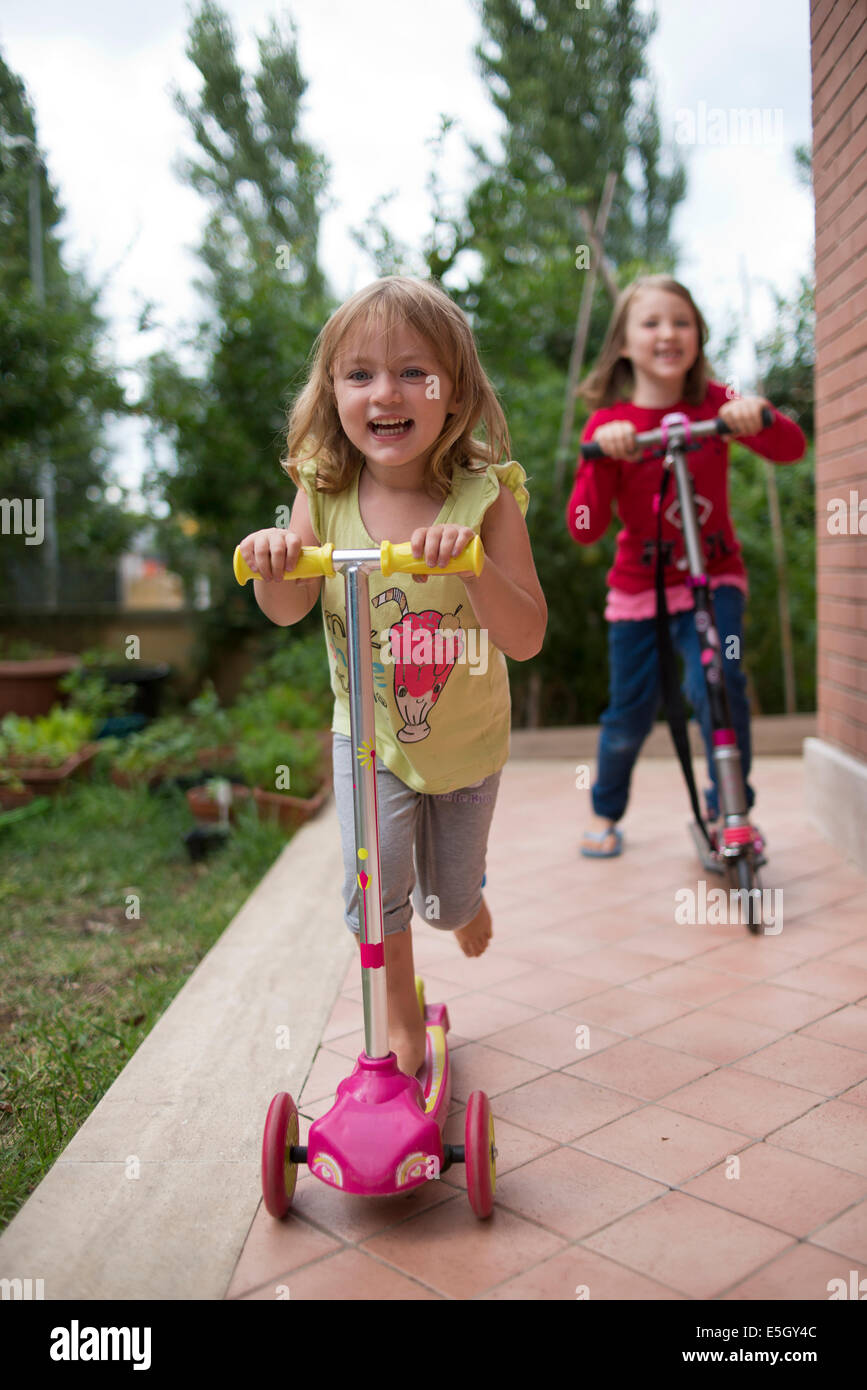 Two young girls riding micro scooters. Stock Photo