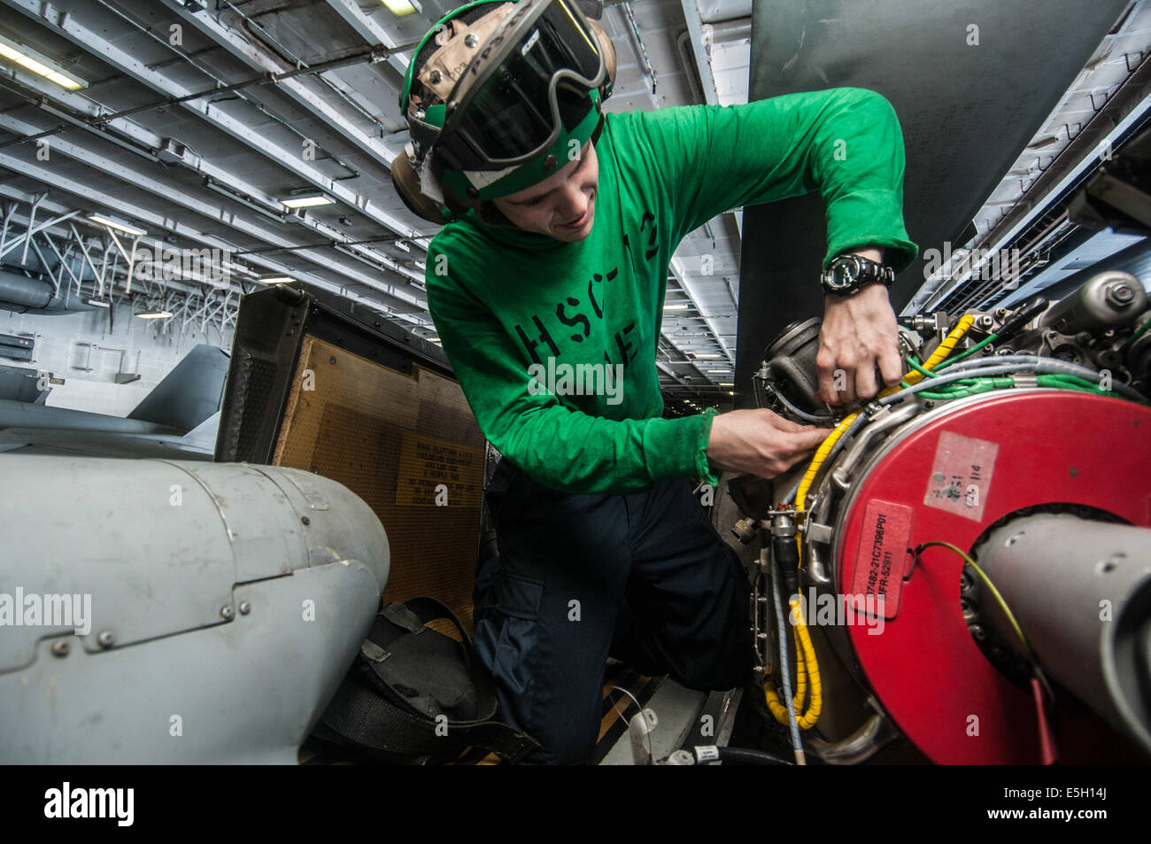 U.S. Navy Aviation Electrician's Mate Airman Spencer Tyo performs maintenance on an engine harness of an MH-60S Seahawk helicop Stock Photo