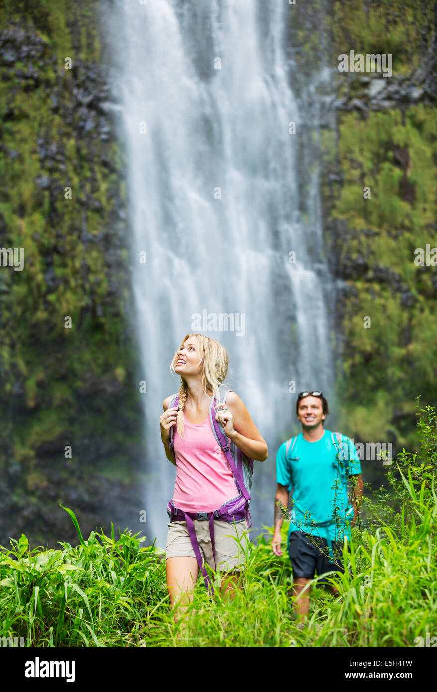 Couple having fun together outdoors on hike to amazing waterfall in Hawaii. Stock Photo