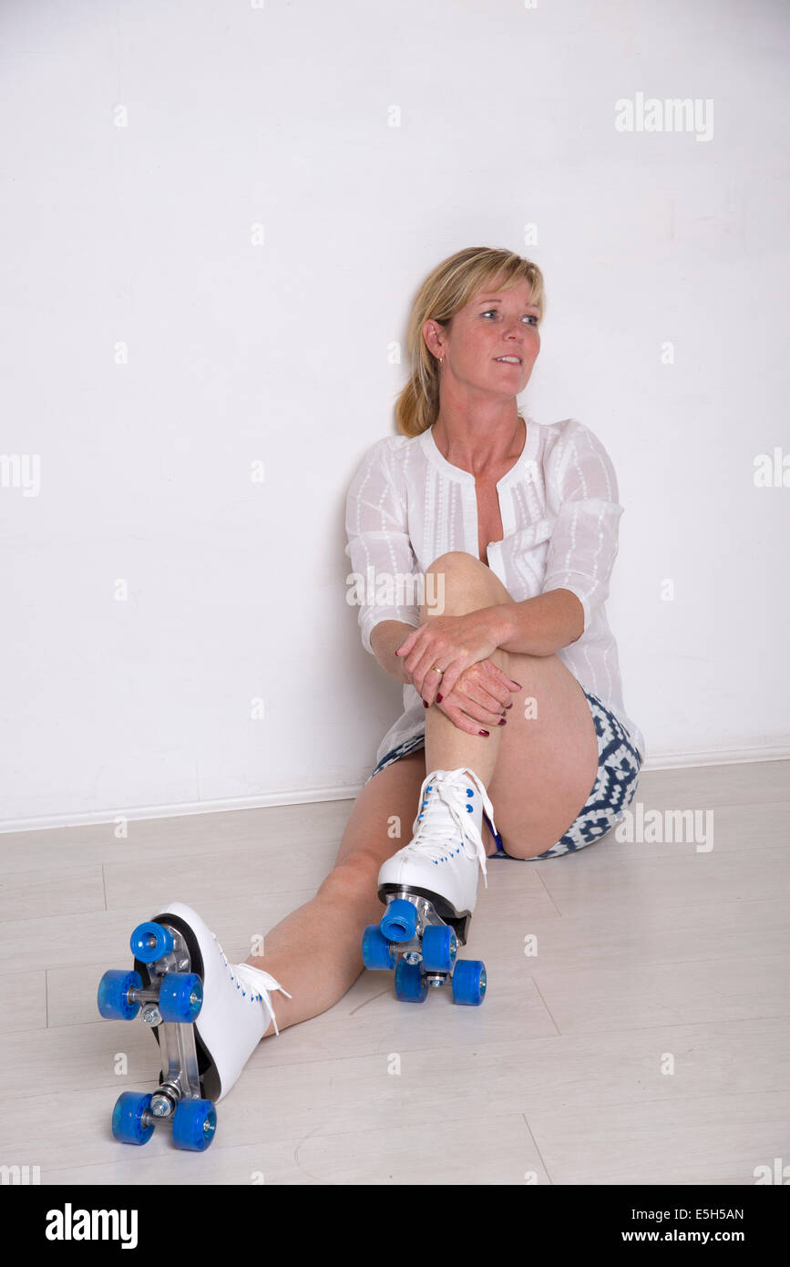 Learning to roller skate a nervous skater leaning on a wall for support Stock Photo