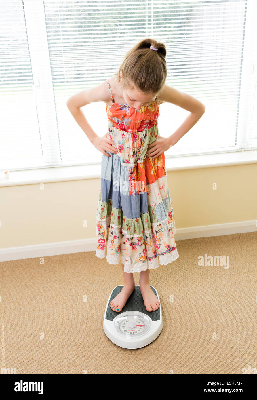 young girl checking her weight on scales Stock Photo