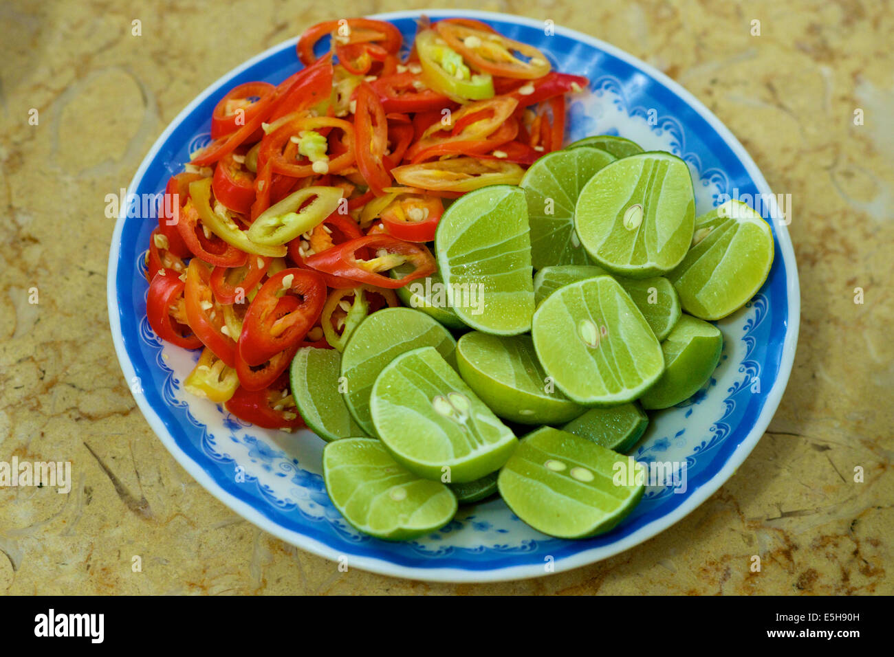 Plate with green limes and red hot chilly peppers in Vietnam Stock Photo