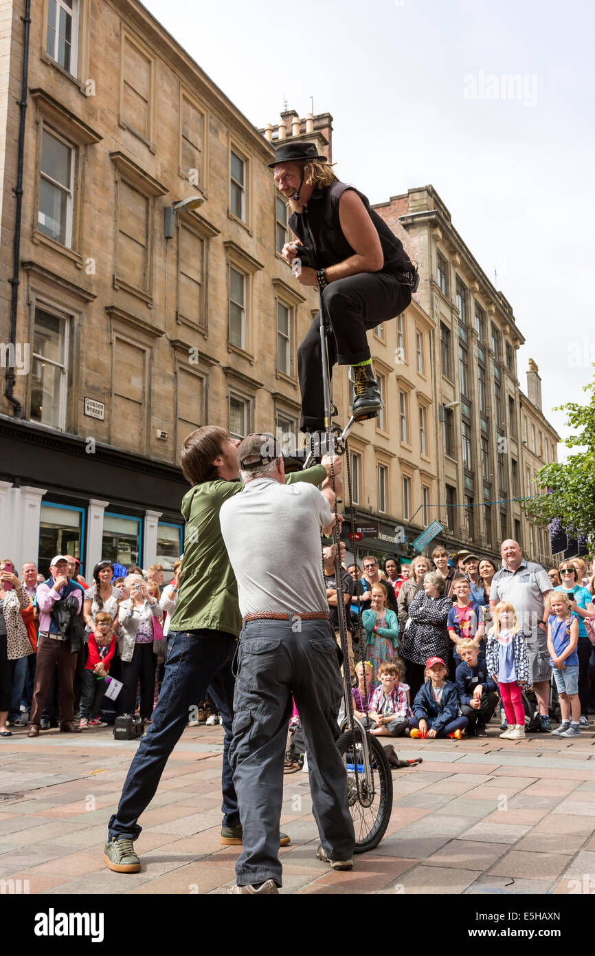 Street entertainer performing with a unicycle and using two members of the audience to help, Buchanan Street, Glasgow, Scotland, Stock Photo