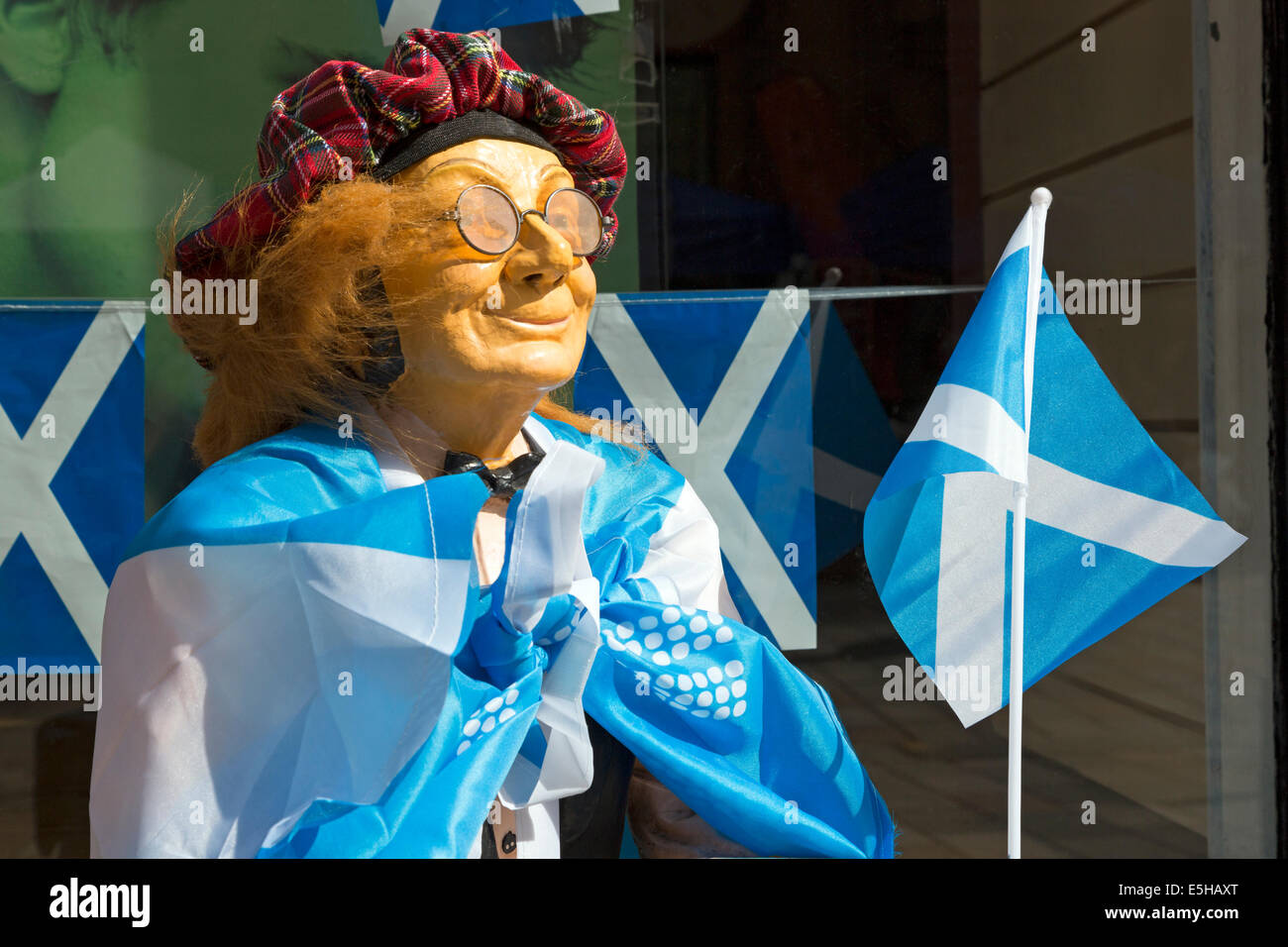 Small mannequin of a man dressed in a tartan hat, covered with a Saltire flag and carrying a small flag, showing support for the Stock Photo