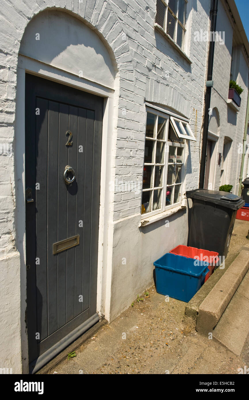 Wooden grey front door of renovated house with recycling bins outside