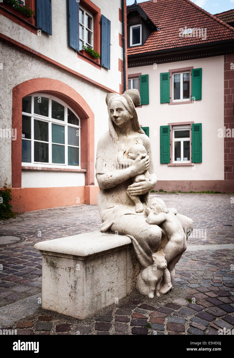 Concrete statue of mother with two children and cat sitting on the bench. Marketplace in Schopfheim, Black Forest Schwarzwald Stock Photo