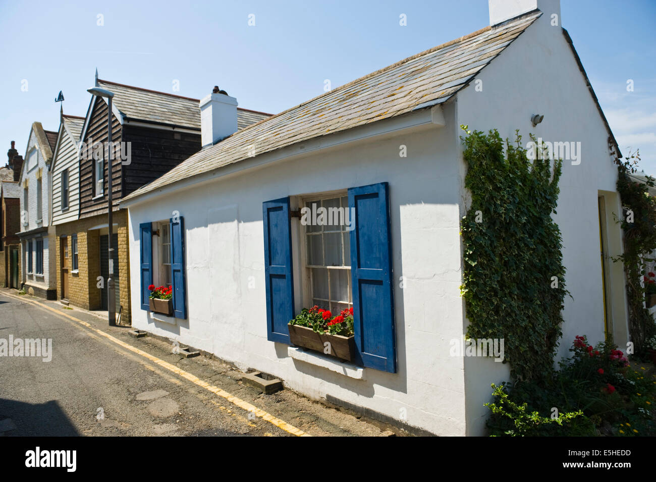 White cottage with blue shutters and typical clapboard houses at Whitstable Kent England UK Stock Photo