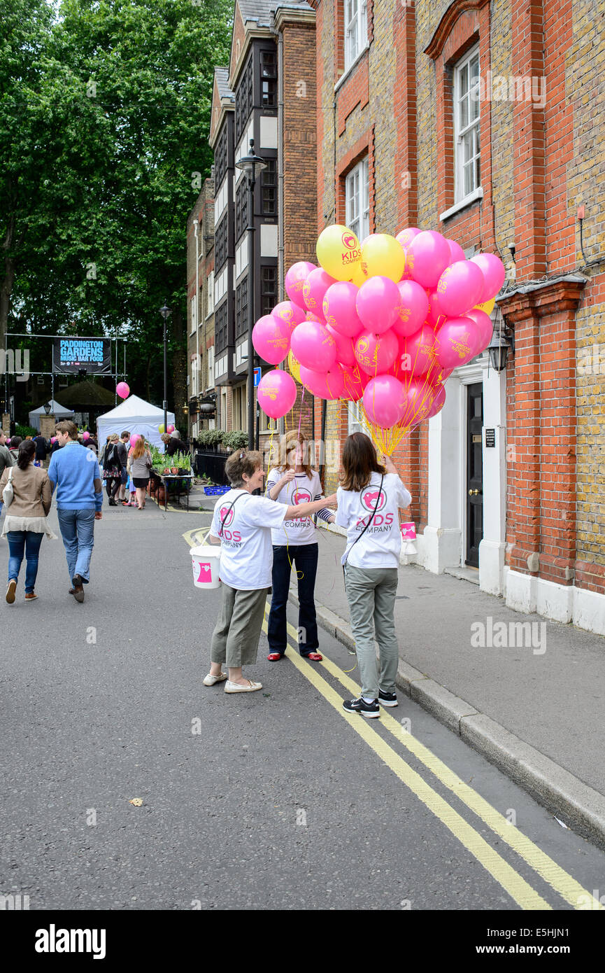 Three 3 female women charity workers collecting money with pink balloons Marylebone a Street Fayre festival party, London, UK. Stock Photo