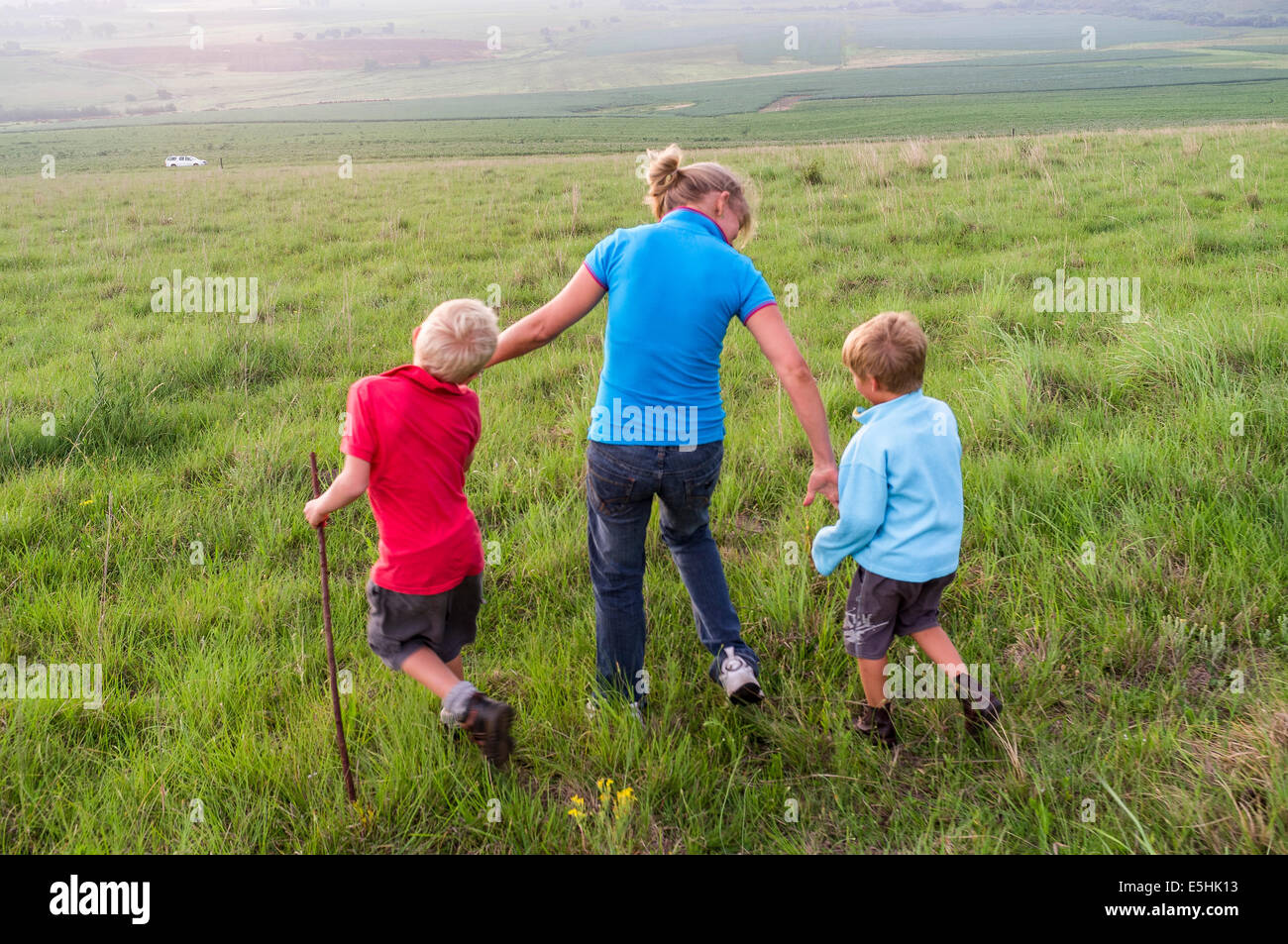 Mother makes an effort to cross field with sons Stock Photo