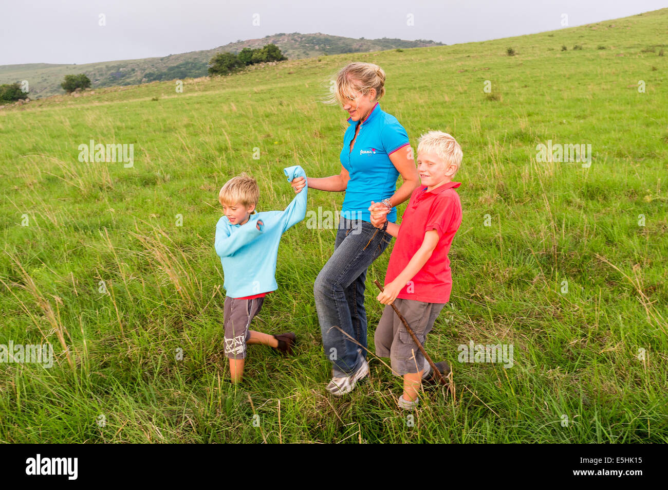 Mother and sons cross field holding hands Stock Photo