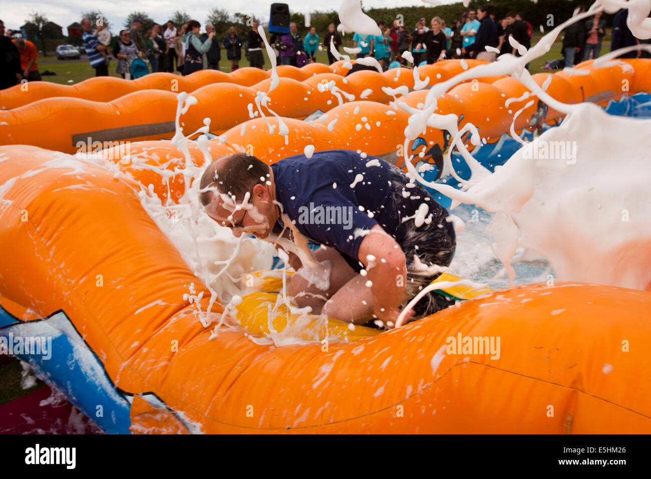 UK, England, Lincolnshire, Cleethorpes, Meridian Park, It’s a Knockout community event, competitor splashing on slide Stock Photo