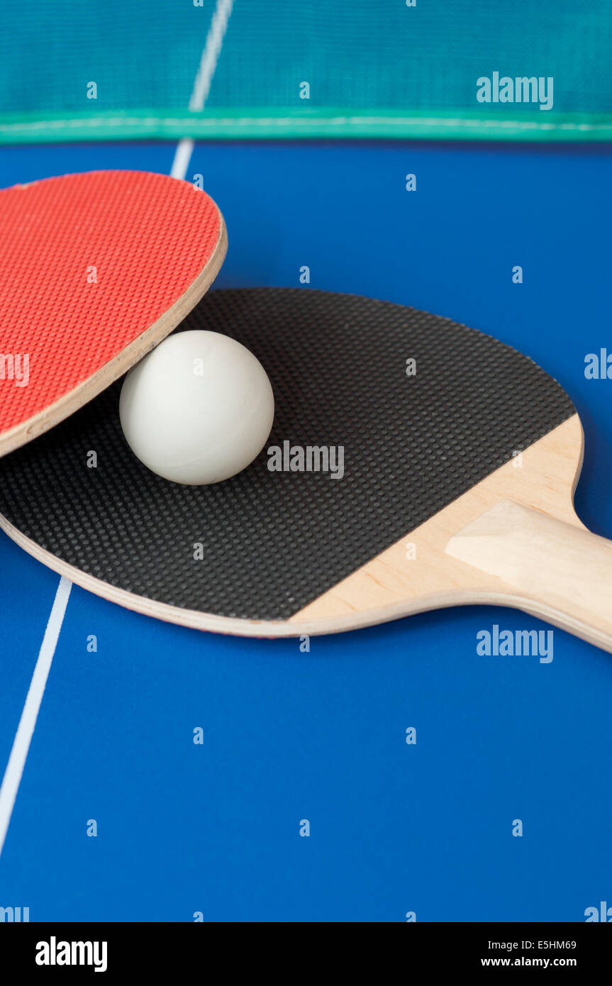 red and black table tennis bats on a blue table with green net in
