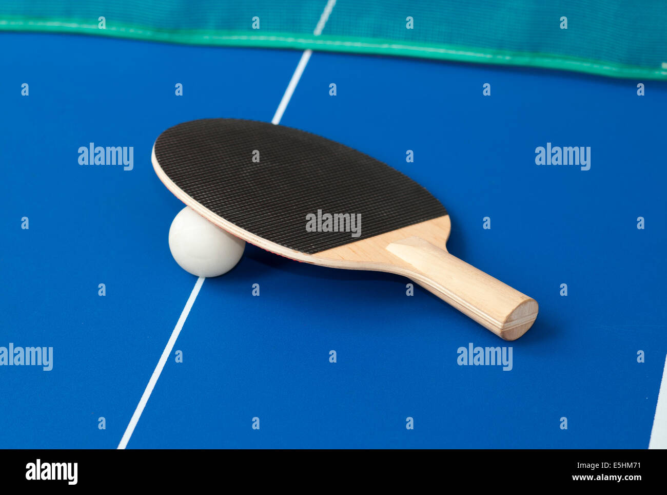 black table tennis bats on a blue table with green net in background