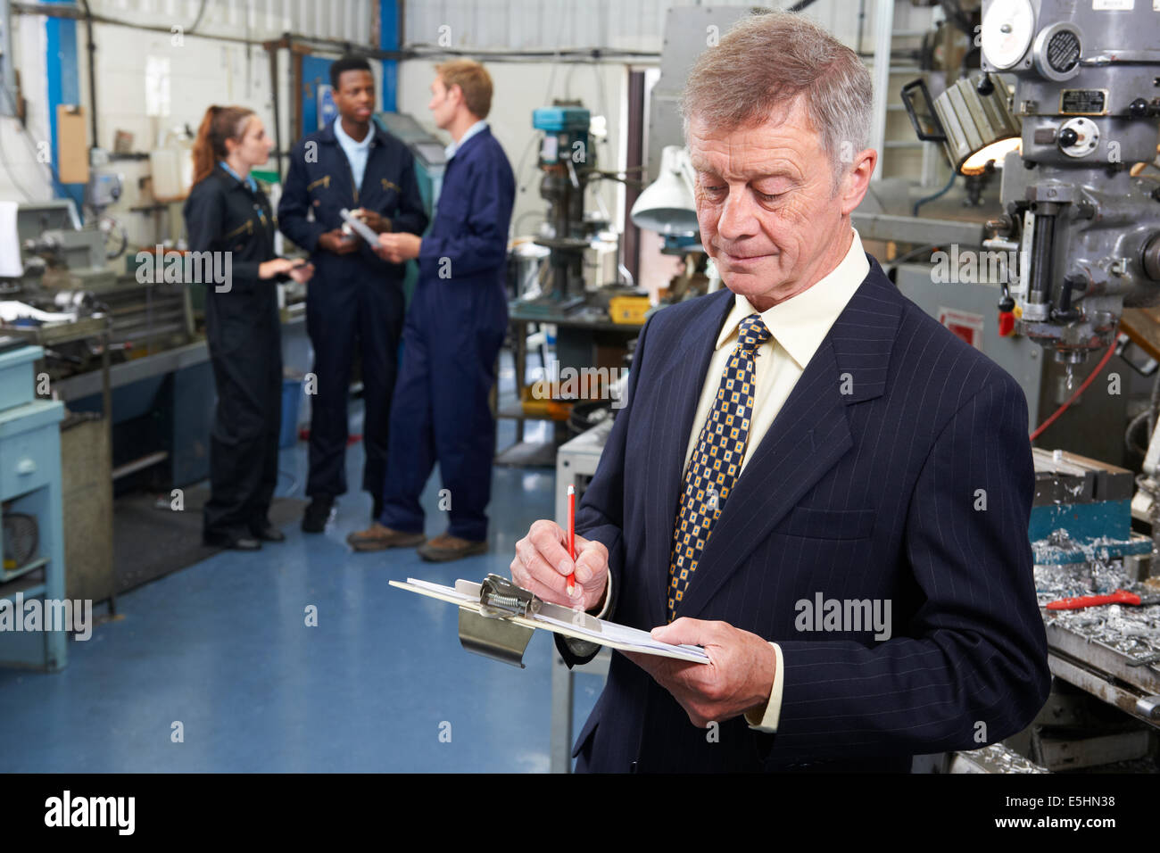 Owner Of Engineering Factory With Staff In Background Stock Photo