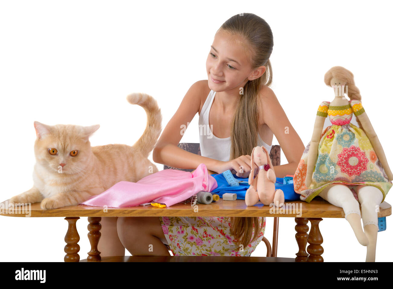 The red cat prevents the girl to sew toys from fabric Stock Photo