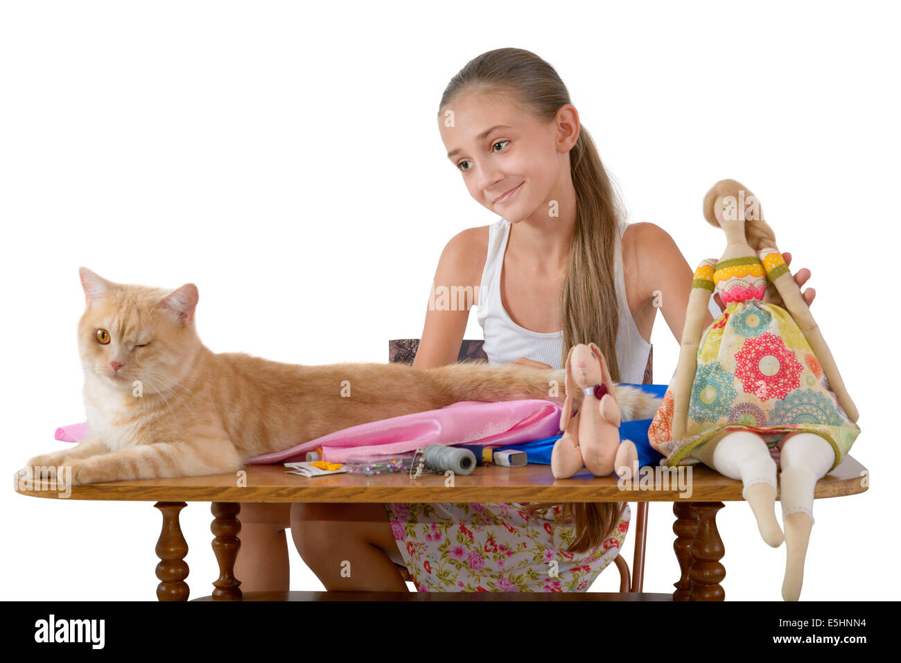 The red cat prevents the girl to sew toys from fabric Stock Photo