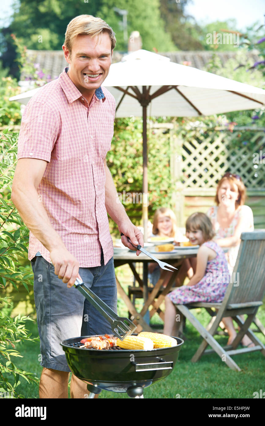Father Cooking Barbeque For Family In Garden At Home Stock Photo