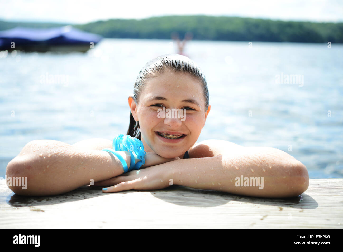 Teen Girl smiling from water by dock on a lake Stock Photo