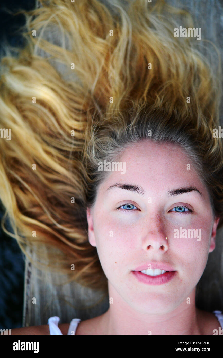 Girl blue eyes blond hair laying down outside looking up Stock Photo