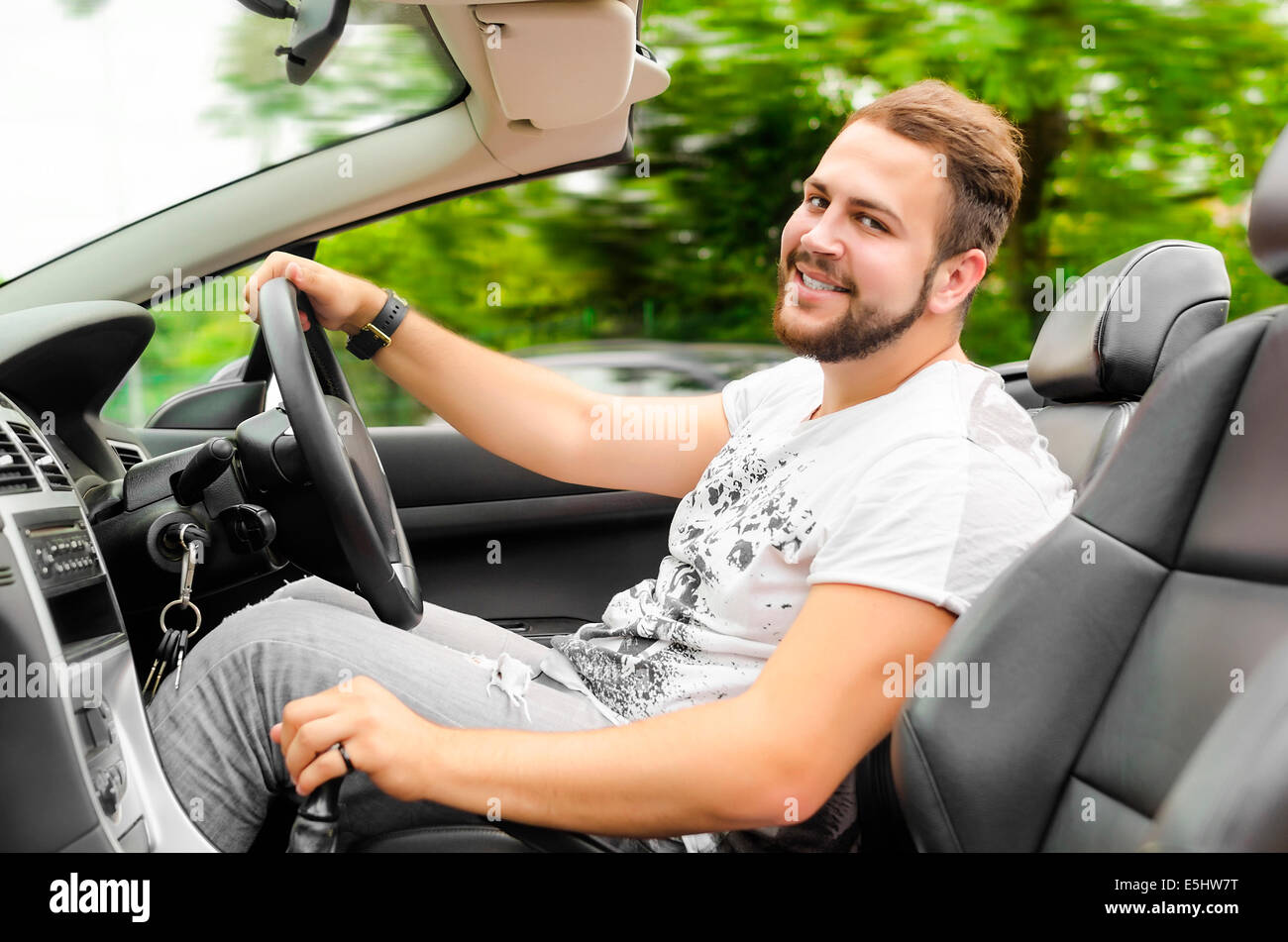 Smiling handsome young man driving cabriolet outdoors Stock Photo