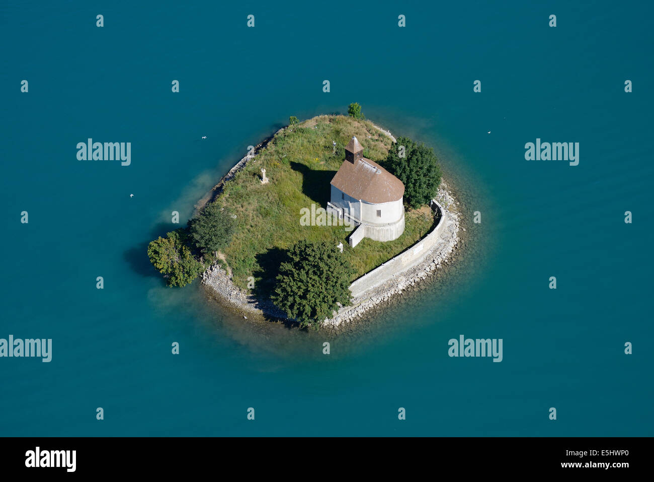 AERIAL VIEW. Chapel on an island surrounded by turquoise waters. Saint-Michel island, Chorges, Lake Serre-Ponçon, Hautes-Alpes, France. Stock Photo