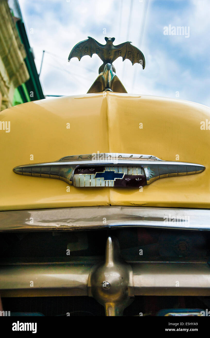 Unique Bacardi rum hood ornament on a yellow 1950s Chevrolet on the streets of Havana, Cuba Stock Photo