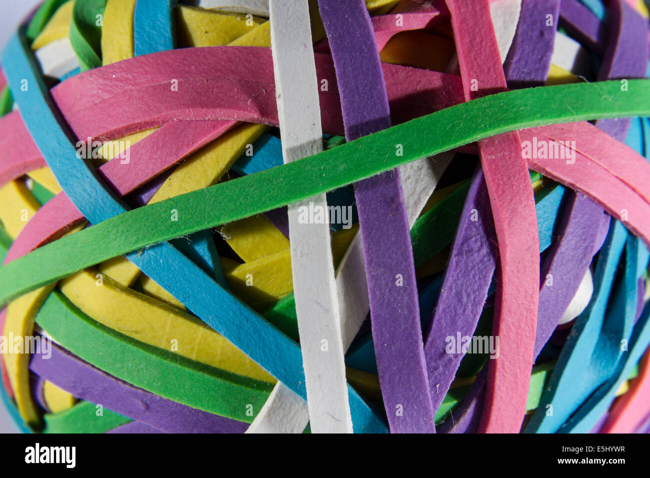 Ball of brightly coloured rubber bands, white background, slight shadow. Stock Photo