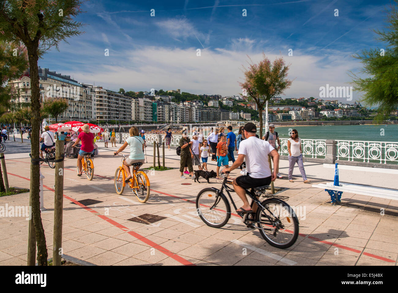 Tourists cycling on the bike lane along the corniche, Donostia San Sebastian, Gipuzkoa, Basque Country, Spain Stock Photo