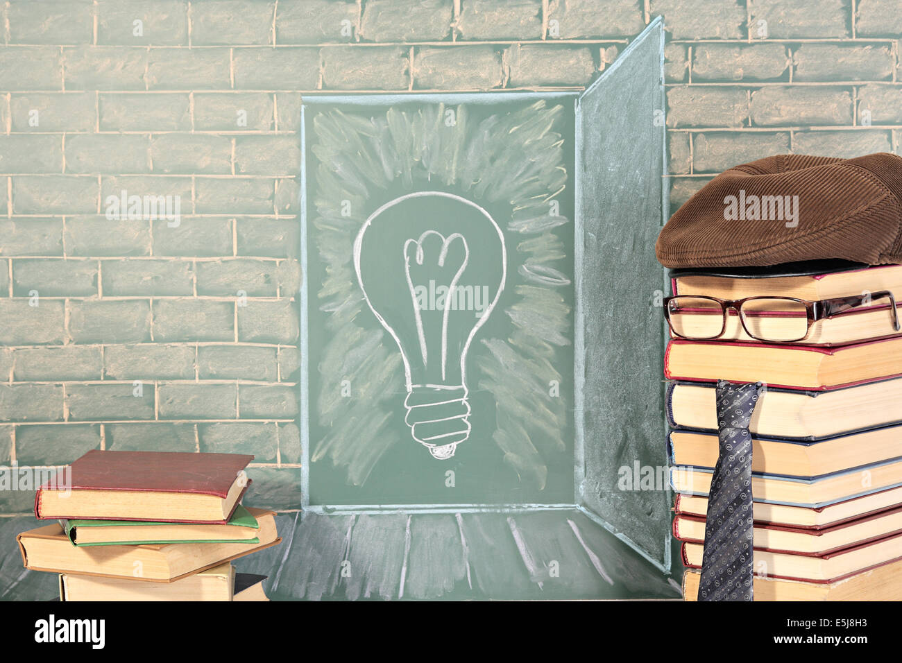 Knowledge idea with illustration of bulb on chalkboard and teacher from books Stock Photo