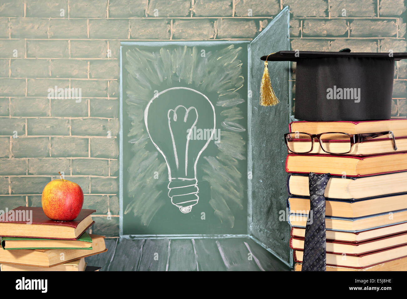 Apple on books and Illustration of bulb on chalkboard behind teacher. Education idea Stock Photo