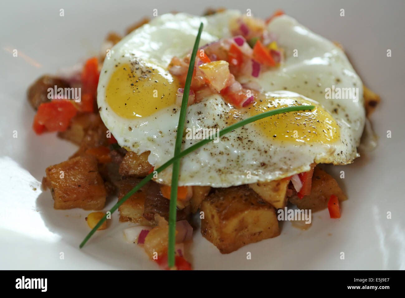 A spicy potato hash topped with two fried eggs. The dish is a popular