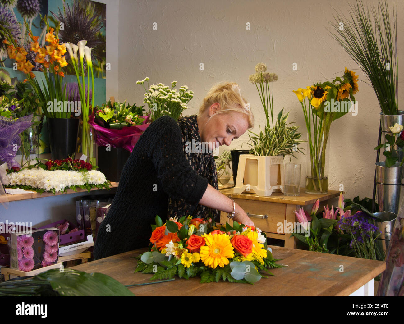 Florist arranging a wreath in a florist's shop with bunches of flowers