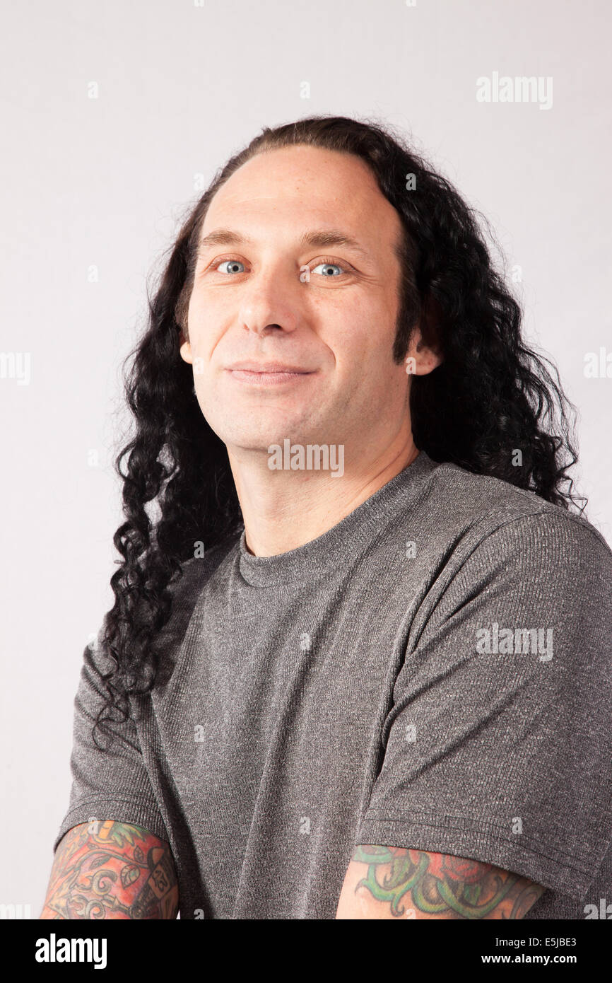 Caucasian male with long hair and gray shirt looking at the camera with a smile Stock Photo