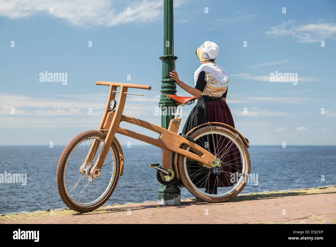 Netherlands, Urk, Bough Bike. The Dutch Design wooden bike is a creation of Jan Gunneweg. Girl in traditional Sunday dress Stock Photo