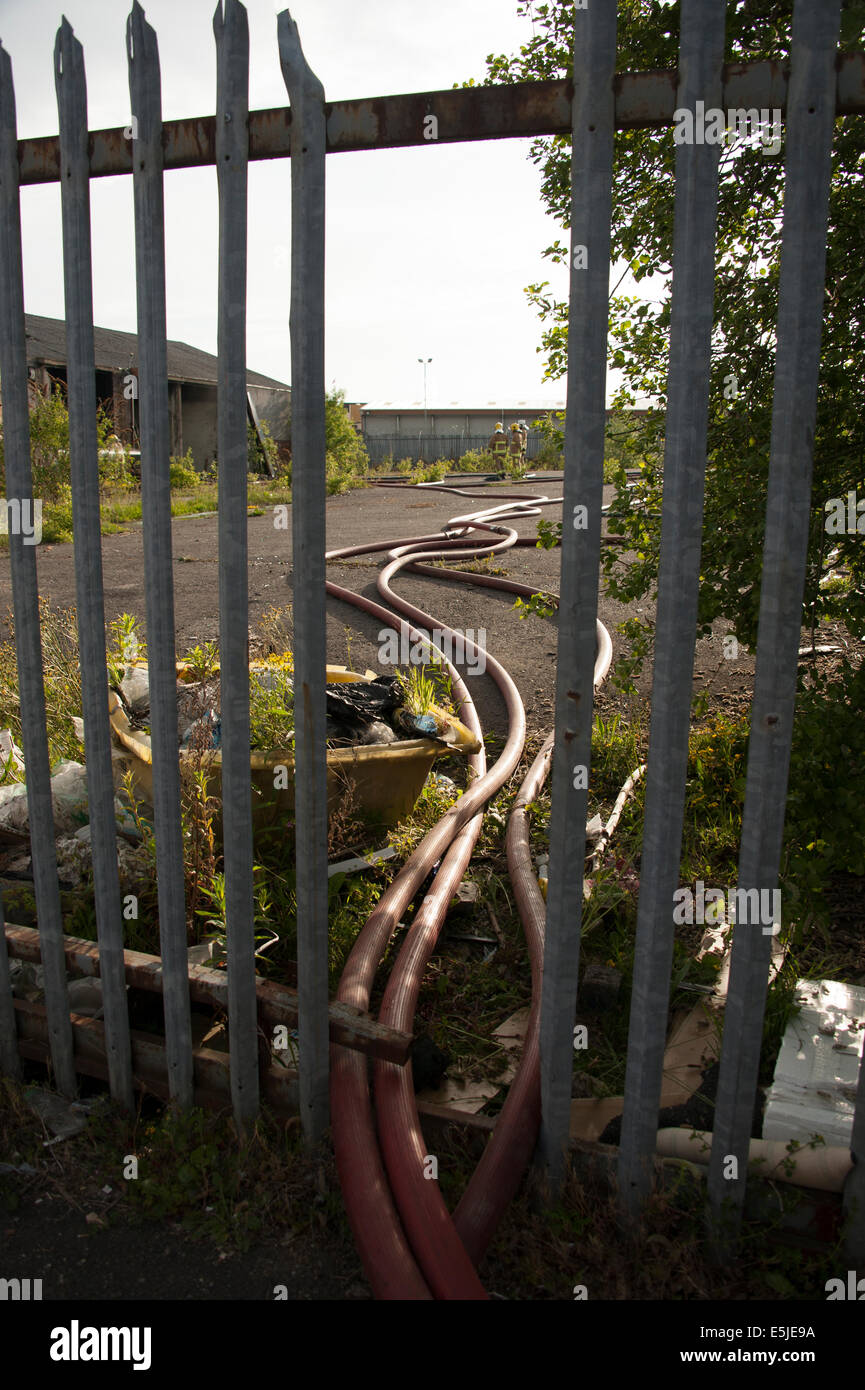 Fire hose main branches through fence railings removed Stock Photo Alamy