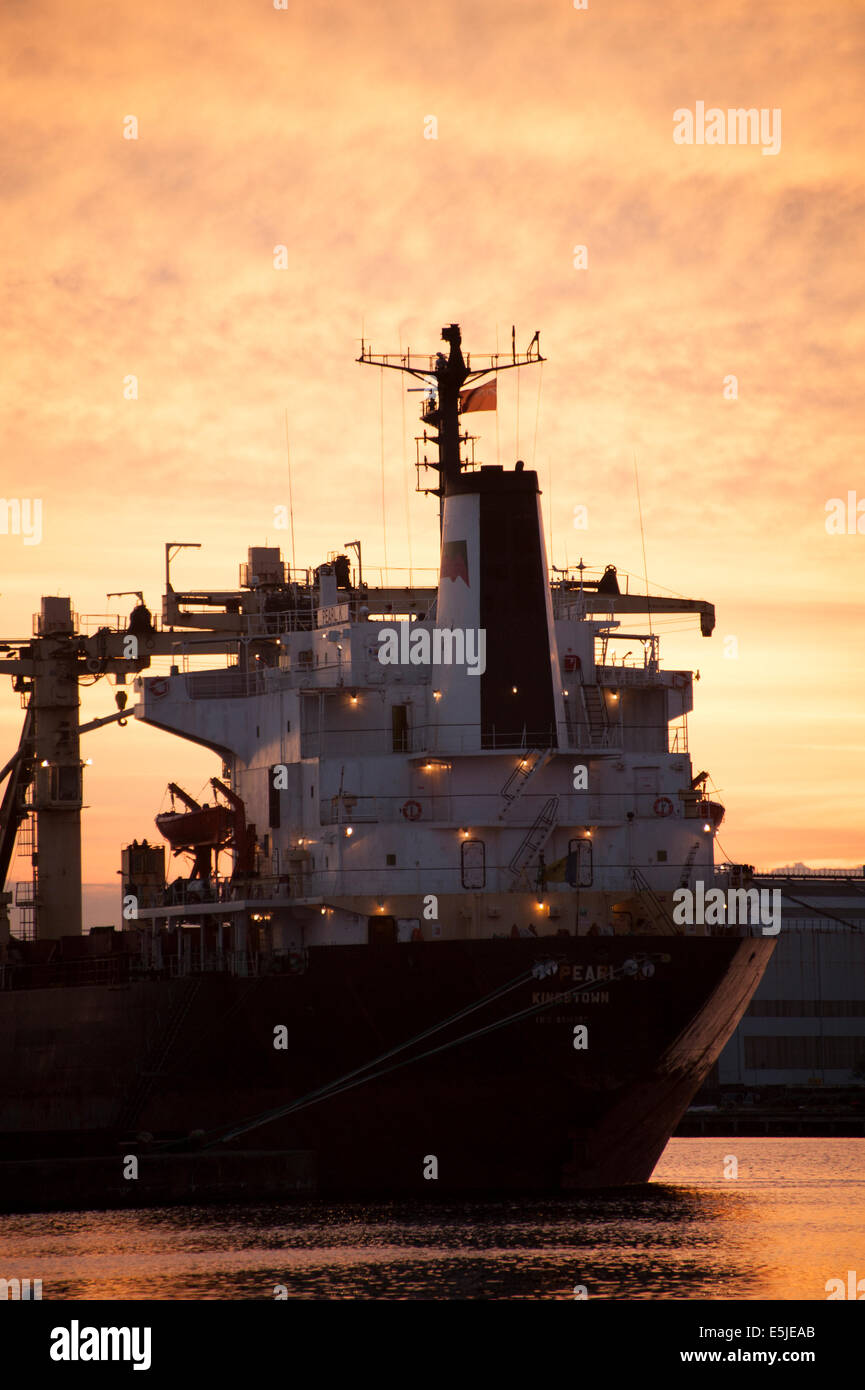 Ship in dock at sunset silhouette red orange sky Stock Photo