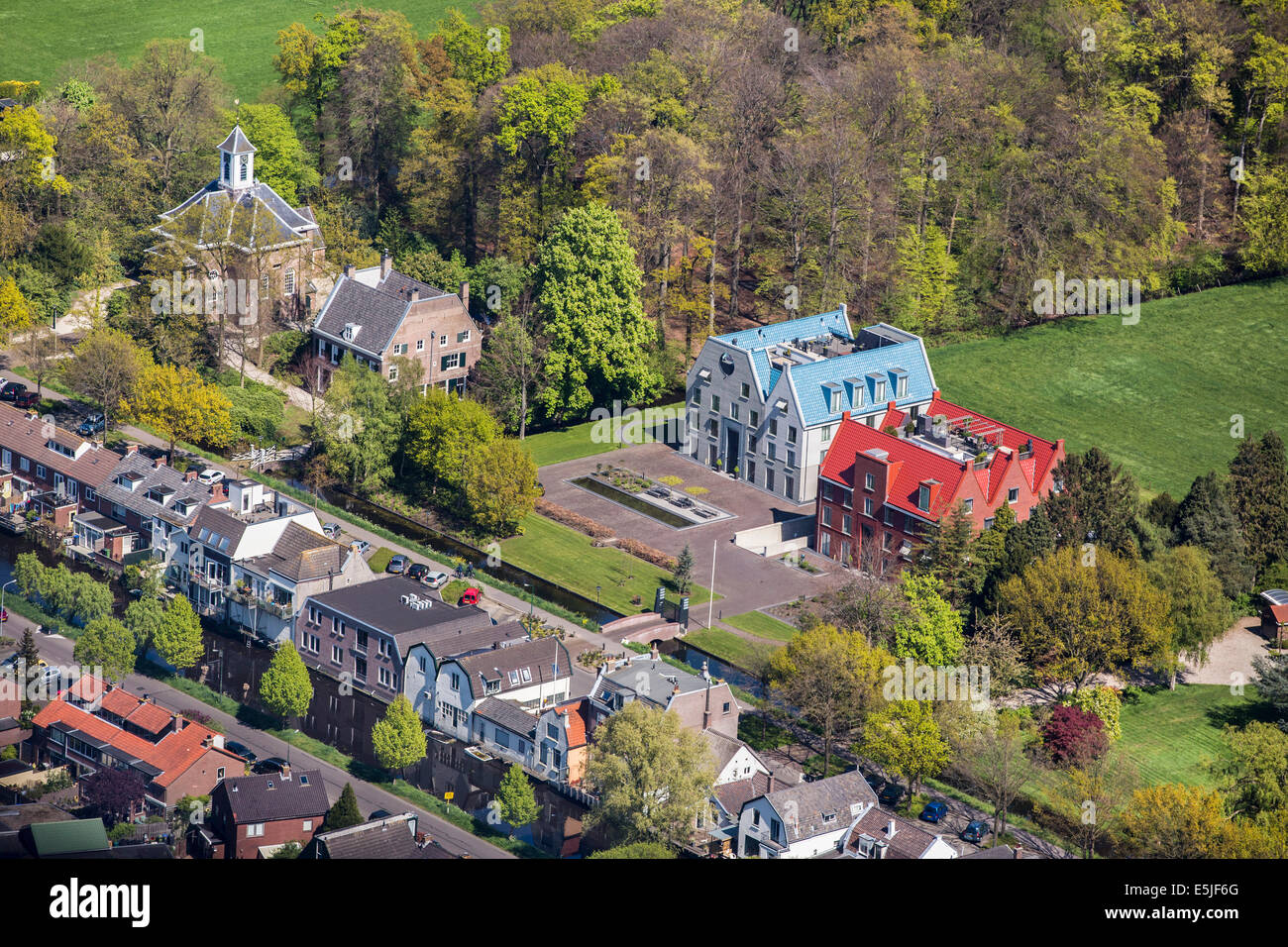 Netherlands, 's-Graveland, Right modern rural estate called Castor and Pollux. Left Dutch Reformed Church from 1658. Aerial Stock Photo