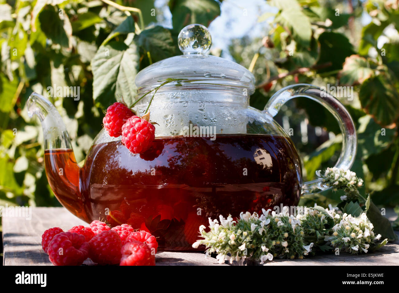 raspberry tea in teapot on wooden desks at nature Stock Photo - Alamy