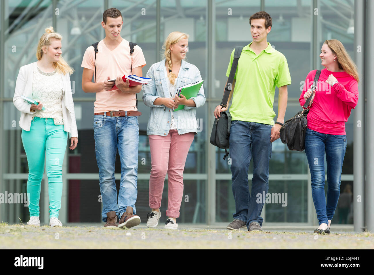 Five students are walking with their school supplies in their hands Stock Photo