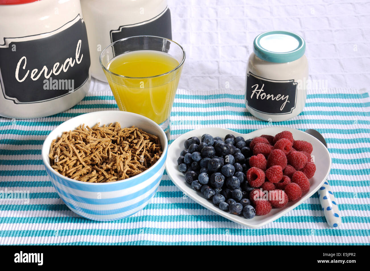 Healthy diet high dietary fiber breakfast with bowl of bran cereal and berries on white heart plate on aqua blue Stock Photo
