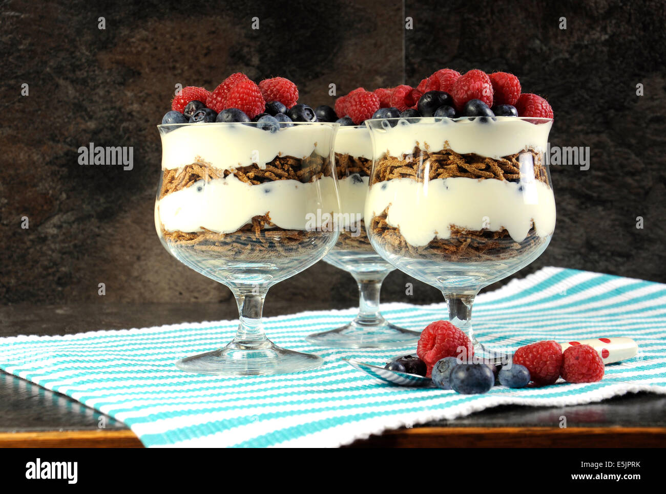 Healthy diet high dietary fiber breakfast with bran cereal, yoghurt and berries trifles on black slate kitchen bench top. Stock Photo