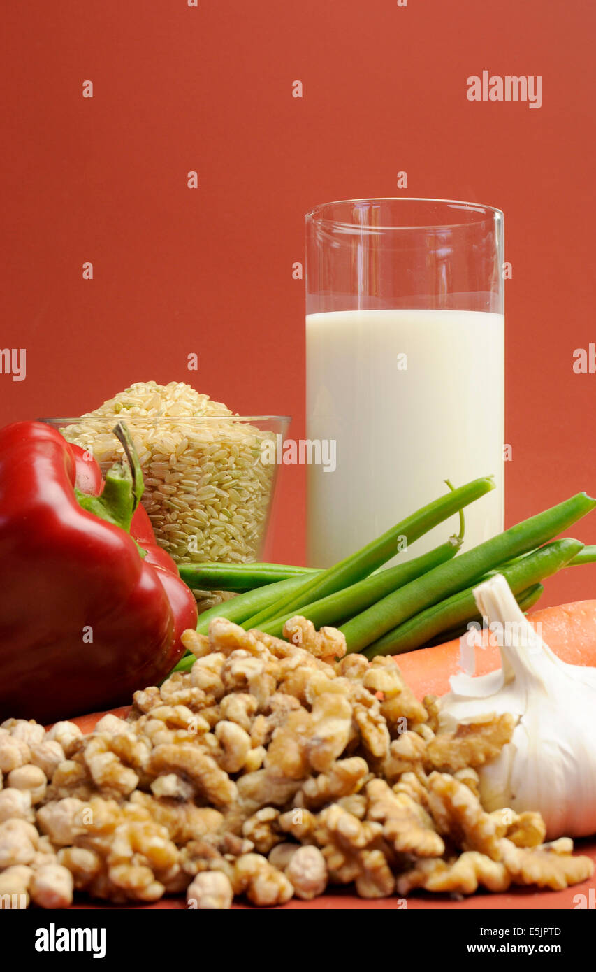 Low GI Foods - milk, brown rice, oatmeal, red capsicum pepper, green beans, garlic, raw carrot, walnuts, chickpeas. Stock Photo