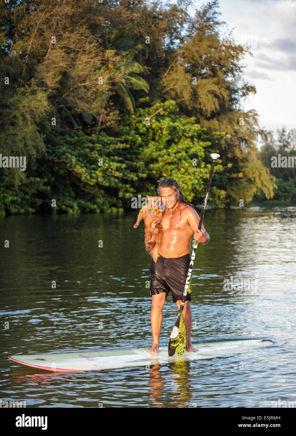Kauai resident and his dog on the Hanalei River; dog accompanies owner when he goes stand up paddle surfing  in Hanalei Bay Stock Photo