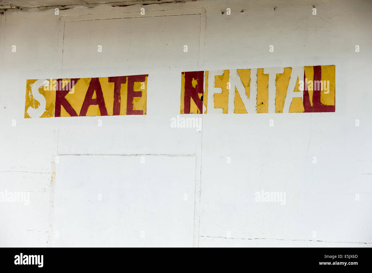 weathered sign 'Skate rental' on the white painted wall Stock Photo